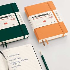 two notebooks with writing on them next to a pen and an empty notepad