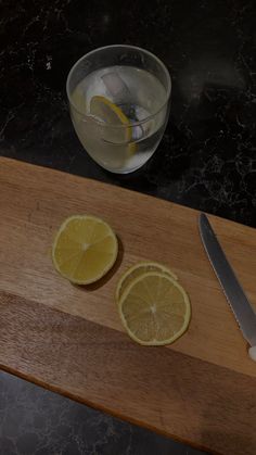 two slices of lemon sitting on top of a wooden cutting board next to a knife