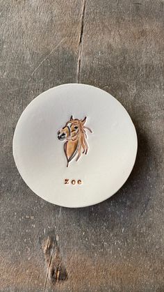 a white plate with a horse head on it sitting on the ground next to a sidewalk