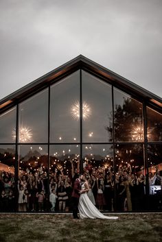 a bride and groom standing in front of a large group of people holding sparklers