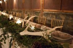 the table is set with deer antlers, greenery and candles for an elegant dinner