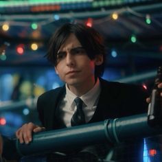 a man in a suit and tie holding a beer bottle looking over a railing at the camera