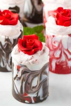 four cupcakes decorated with red and white frosting, one has a rose on top