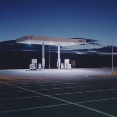 an empty gas station at night with no one around the gas pumps on the ground