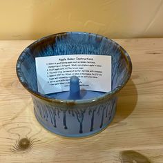 a blue bowl sitting on top of a wooden table next to a sign with writing