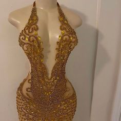 a mannequin with gold beading on it's neck and back, in front of a white wall