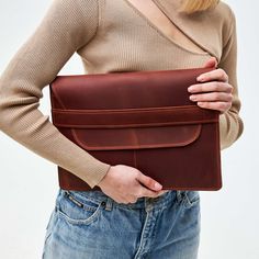 a woman holding a brown leather bag in her hands