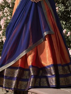 Embrace the vibrant elegance of our orange Kanchipuram silk lehenga, exquisitely paired with a blue Kanchipuram silk choli and a matching blue georgette dupatta. This ensemble showcases the rich heritage and craftsmanship of traditional Indian attire, featuring intricate zari weaving work that exudes luxury and sophistication. The orange lehenga, with its striking color and detailed design, is the perfect choice for making a bold statement at any grand event.
The lehenga offers a generous 3.70-m Gold Half Saree, Lehenga Blue, Orange Lehenga, Silk Lehenga Choli, Half Saree Lehenga, Georgette Dupatta, Baby Dress Design, Dress Indian, Dress Indian Style