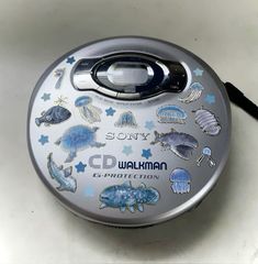 a round metal container with various stickers on it's lid sitting on a table