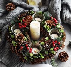 a christmas wreath with candles and pine cones