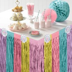 a table topped with cake and cupcakes next to a dessert bar covered in tassels