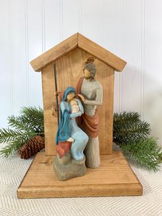 a figurine of a man and woman in a nativity scene with pine branches