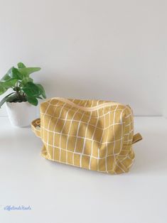 a yellow bag sitting on top of a white table next to a potted plant