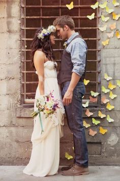 a man and woman standing next to each other in front of a wall with butterflies on it