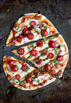 a sliced pizza with tomatoes and basil on it