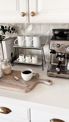 a kitchen counter with coffee maker, cups and utensils on top of it