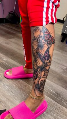 a woman's legs with butterflies and flowers on her left leg, while wearing pink sandals