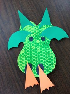 a paper cut out of a green dragon with two orange horns on it's head