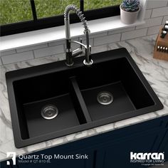 a black double sink with two faucets on the side and a window behind it