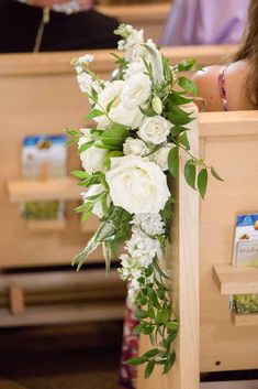 white flowers and greenery are placed on the pews at a church wedding ceremony