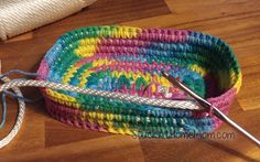 a crocheted basket with a pair of scissors on the floor next to it