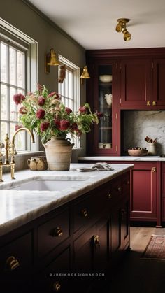 a kitchen with red cabinets and marble counter tops, gold faucets and brass fixtures