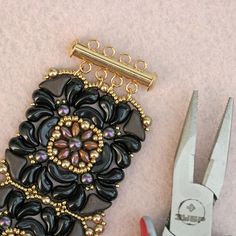 a pair of scissors and some beading on a pink table next to a piece of jewelry