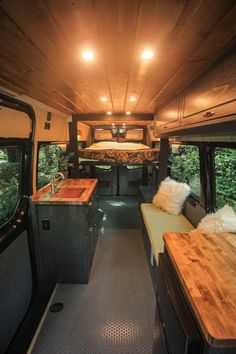 an interior view of a camper van with wood flooring and counter tops in the foreground