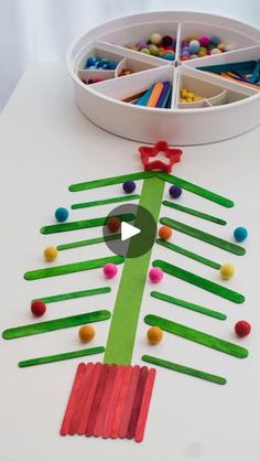 a christmas tree made out of popsicle sticks and colored pencils on a table