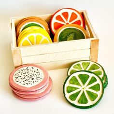 four slices of fruit are in a wooden box on a white surface, and one is cut in half