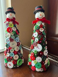 two snowmen made out of buttons sitting next to each other on top of a table