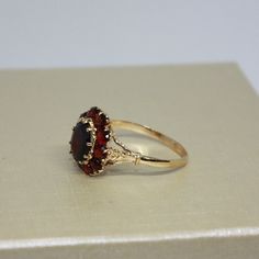 Vintage, Beautiful estate, handcrafted Brown Garnet ring for women, made from 18k solid Yellow gold, Oval shaped natural Garnet in a center surrounded by 10 round smaller stones (Garnets), set on prongs. Total weight of the item is 4g. Polished finish. Excellent condition. Please look at all pictures and If you have any questions, ask, we will be happy to assist you. Note: Store certificate is available, please ask. Item will come in a nice gift box, that will make it look even more special for a someone you love. Item priced for sale. Thank you for shopping with us. Georgian Era Engagement Ring, Red Engagement Ring Unique, Luxury Garnet Ring With Center Stone, Formal Garnet Ring With Center Stone, Luxury Garnet Rings Hallmarked, Luxury Hallmarked Garnet Rings, Luxury Yellow Gold Rings With Garnet, Elegant Multi-stone Garnet Rings, Formal Garnet Rings Fine Jewelry