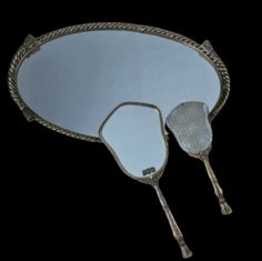 two silver spoons and a mirror on a black background