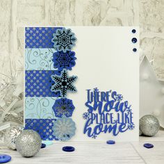 a blue and white christmas card with snowflakes on it, surrounded by silver ornaments