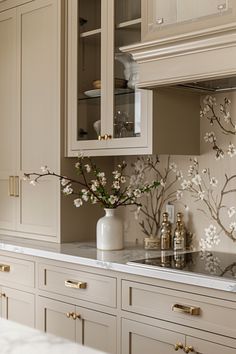 a kitchen with white cabinets and flowers on the counter