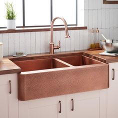 a copper sink in a kitchen with white cabinets