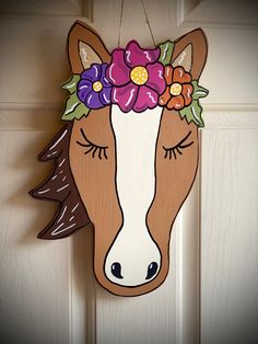 a wooden horse head with flowers on it's forehead hanging from a door handle