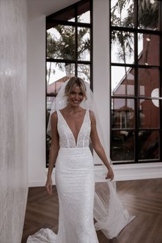 a woman in a white wedding dress is walking through the room with her veil over her head