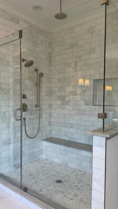 a walk in shower sitting next to a white tiled wall and floor with glass doors