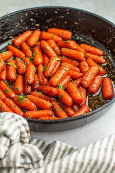 a pan filled with cooked carrots on top of a counter next to a towel