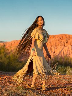 a woman with long hair walking in the desert