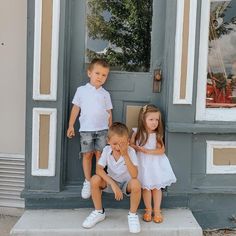 three children are sitting on the step of a building with their hands in their mouths