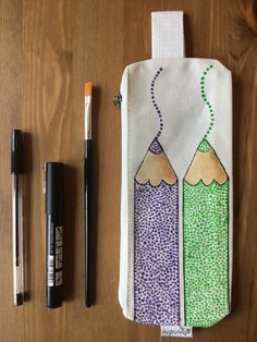 two pencils and markers are sitting on a table next to a zippered pouch