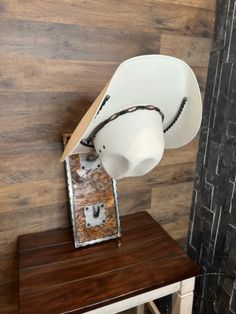 a white hat sitting on top of a wooden table next to a wall mounted speaker