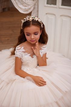 Elevate the elegance of your little one's special day with the Pentelei Couture 3627 Lace Embroidered Tulle Flower Girl Dress. This stunning gown features a sheer illusion off the shoulder neckline adorned with intricate embroidered crystal accents, adding a touch of sparkle to her look. The voluminous floor length skirt is sure to make her feel like a princess, with multiple tiers of ruffled tulle creating a dreamy and ethereal silhouette. Let her shine and steal the show in this exquisite ense First Communion Pictures, 1st Communion Dresses, Designer First Communion Dresses, Comunion Dress, Communion Hair, Communion Headpiece, Communion Ideas, Girls Communion Dresses, Flower Girl Crown