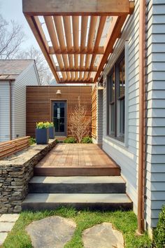 an outdoor patio with stone steps and wooden pergolan over the walkway leading up to it