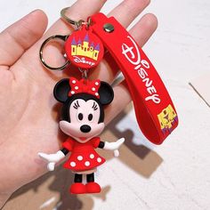 a hand holding a mickey mouse keychain with a red tag attached to it