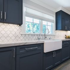 a kitchen with dark blue cabinets and white counter tops is seen in this image from the front view