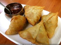 several pastries on a plate with dipping sauce