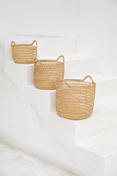 three woven baskets sitting on the side of some white steps, with one basket in the middle